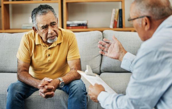 Two men speaking together in a therapist's office.