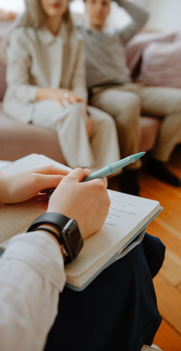 A couple sitting on a couch while speaking to a therapist.